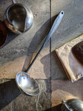 (Modern colonial-style handmade ladle combining polished and forged stainless steel elements.)