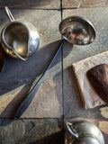 (Modern colonial-style handmade ladle combining polished and forged stainless steel elements.)