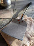 (Close-up of a hammered and stonewashed stainless spatula blade riveted with copper, hand-forged in Quebec.)