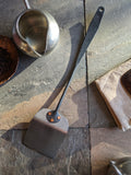 (Back side of artisan stainless steel spatula made at Strobus Forge, Quebec, featuring copper rivets and a black-forged finish.)