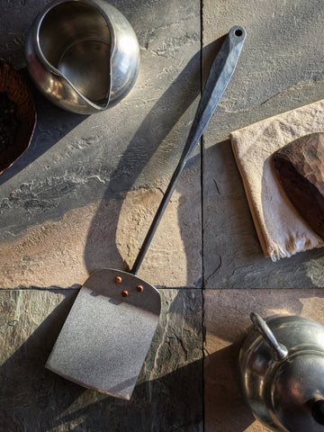 (Hand-forged stainless steel spatula with a black-forged handle and hammered blade.)