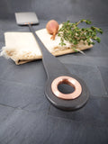 closeup of hand forged barbecue spatula handle showing decorative copper eyelet