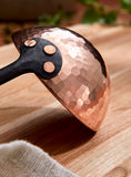 Closeup view of hand hammered copper ladle bowl showing texture and rivets