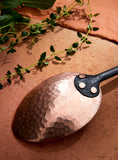 Closeup of oblong serving spoon bowl made out of hand hammered copper