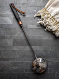 Hand-forged stainless steel sauna ladle with polished finish and black ash handle, made at Strobus Forge in Quebec. Back view